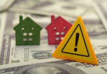 Colorful house models and a warning sign on dollar bills