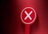 Red sign with a white cross symbol on a dark background