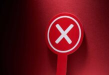 Red sign with a white cross symbol on a dark background