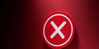 Red sign with a white cross symbol on a dark background