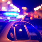 Traffic Stop Uncovers CHILLING Attack Plot Police car with flashing blue lights at night.