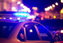 Police car with flashing blue lights at night.