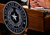 DEXIT Wave Slams Delaware – Texas Wins Seal of Texas Governor on wooden podium.
