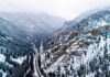 Snowy valley with road winding through frozen forest