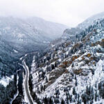 Snowy valley with road winding through frozen forest