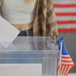Person casting vote into a ballot box.