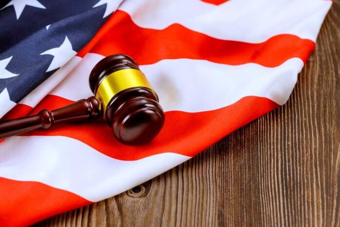 Justice,Wooden,Gavel,Rests,On,Draped,American,Flag,,Symbolizing,Justice, A gavel resting on an American flag