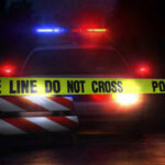 VIDEO: Wanted Gunman’s Deadly Rampage Police car with flashing lights behind caution tape.