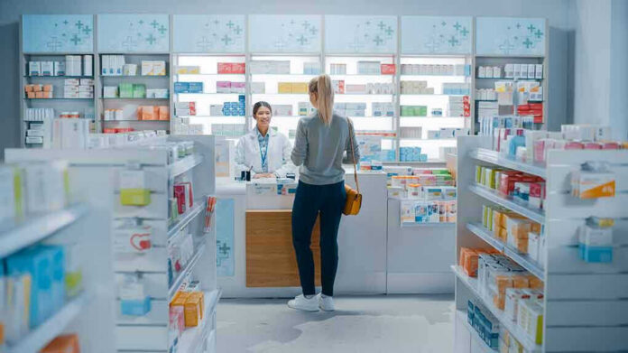 1952231947-1 Customer talking to pharmacist at a bright pharmacy.