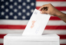 Shock Poll: Democrats Surge Eight? Hand inserting mail-in ballot envelope into ballot box