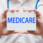 A medical professional holding a sign that says MEDICARE