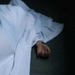 VIDEO: Pronounced Dead, Then… Gasping In The Morgue Hand emerging from under white sheet on dark surface.
