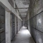 Empty prison corridor with barred cells on either side