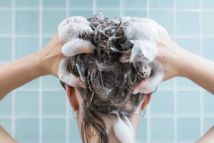 Girl,Washes,Her,Hair,With,Shampoo,On,Blue,Background,,Back Person washing hair with shampoo lather
