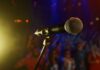 Beloved Singing Icon Vanishes — Now We Know Why Close-up of a microphone in front of a blurred audience at a concert