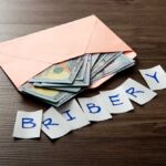 Congress Cash Games Crippled — Or Not? Envelope with cash and notes spelling bribery on wooden table