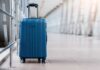 Airport Ambushes Rattle Visa Holders A blue suitcase with wheels positioned in an airport terminal