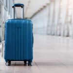 Airport Ambushes Rattle Visa Holders A blue suitcase with wheels positioned in an airport terminal