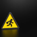 Workers Vanish — Markets Cheer Anyway Yellow triangular warning sign with walking figure and briefcase on black background