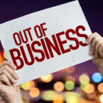 Hands holding an out of business sign