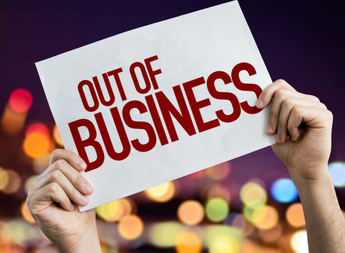Hands holding an out of business sign