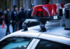 Empire State Chaos: Spire Stunt Triggers Felonies Police car lights with officers blurred in background.