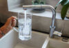NOW: Water Rationing RETURNS! Hand filling pitcher with water from faucet.