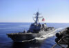 Warship with American flag sailing in the ocean.