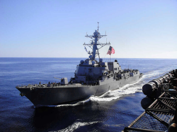 Warship with American flag sailing in the ocean.