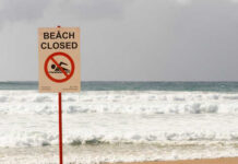 Sign indicating the beach is closed with a no swimming symbol