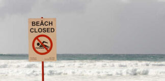 Sign indicating the beach is closed with a no swimming symbol