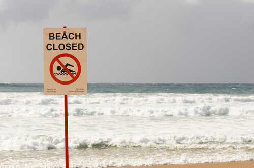 Sign indicating the beach is closed with a no swimming symbol