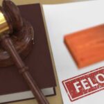 Judge's gavel on book beside paper stamped felony