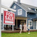 For sale sign in front of a house with potential buyers discussing