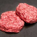 Burger Shake-Up: Grass-Fed Goes National Two raw ground meat patties on a dark surface