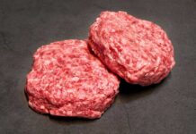 Two raw ground meat patties on a dark surface