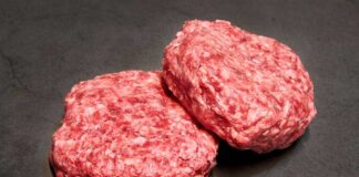 Two raw ground meat patties on a dark surface