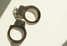 A pair of metallic handcuffs resting on a light surface