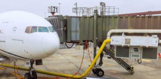 Airplane parked at the gate with boarding bridge and ground equipment