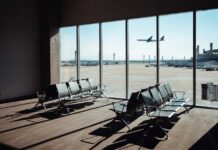 View of an airport waiting area with an airplane taking off in the background
