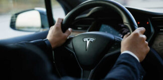 Person driving a Tesla car steering wheel