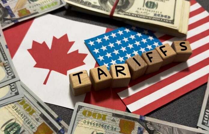 Wooden blocks spelling tariffs on U.S. and Canadian flags with dollar bills