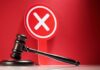Judge's gavel with red cross sign in background