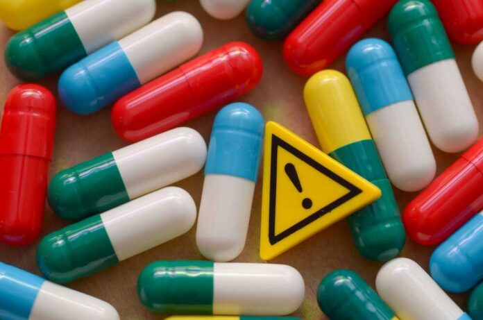 Colorful capsules scattered around a yellow warning sign
