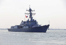 Naval destroyer with crew on deck sailing in open water