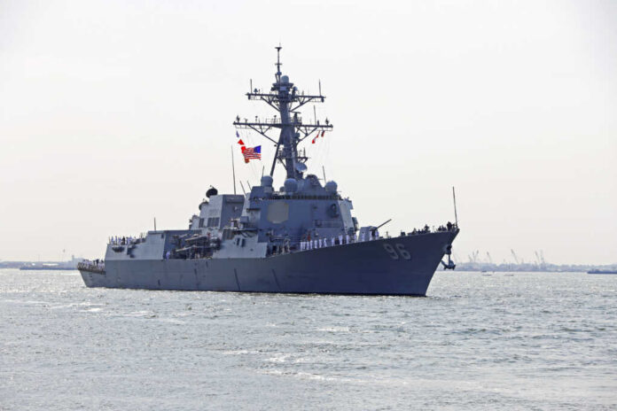 Naval destroyer with crew on deck sailing in open water