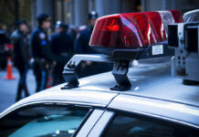 Pill Trail Twist in Star’s Death? Police car roof with lights, officers in background.