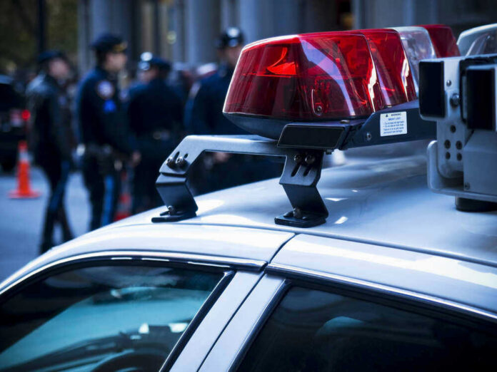 shutterstock_46269745 Police car roof with lights, officers in background.