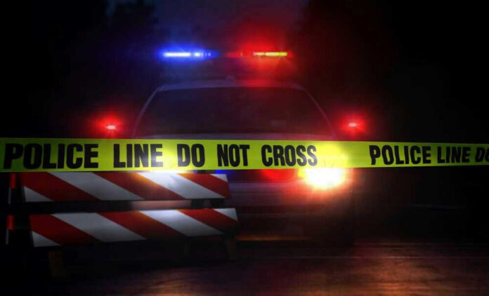 Police car with flashing lights behind caution tape.