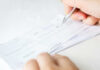 Person signing a check on a white background.